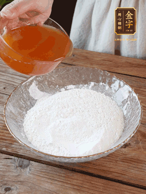 轉(zhuǎn)化糖漿、枧水、花生油攪拌均勻，加入面粉混合，醒發(fā)2小時(shí)。捏成23g一個(gè)的小球